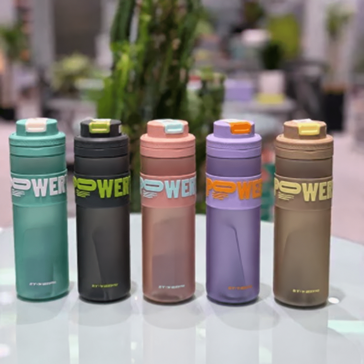 Five colorful bottles on a reflective tabletop قمقمه دورسیلیکونی 820 میل آبین - تصویر 1